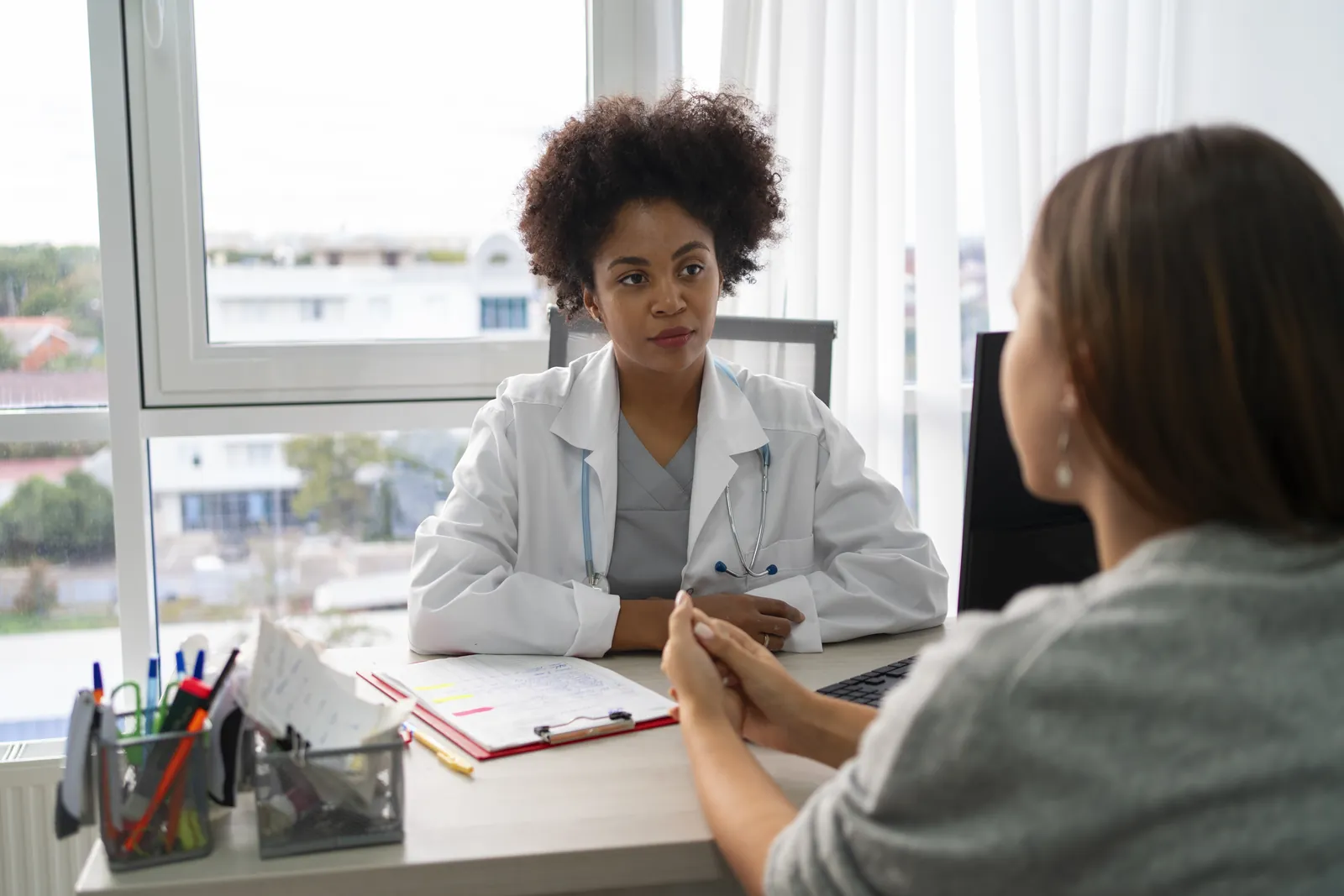 Médica conversando com uma paciente no consultório