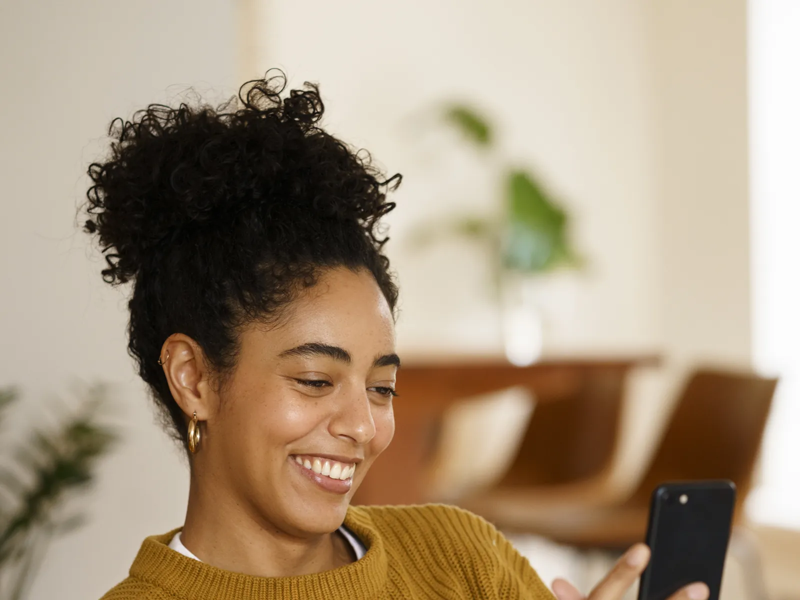 Mulher sorrindo enquanto preenche o formulário no celular